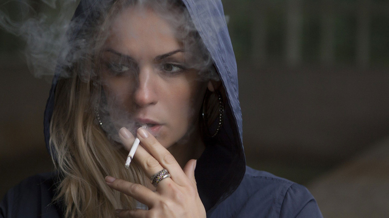 Jugendliche Raucherin mit blauem Kaputzenpullover