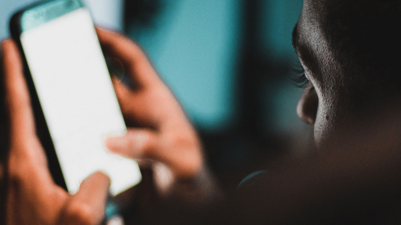 Junge nutzt Smartphone spätabends im Bett